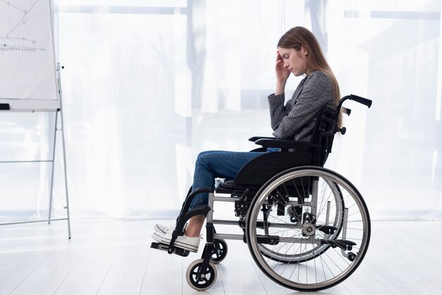 Mulher triste de tiro completo em cadeira de rodas