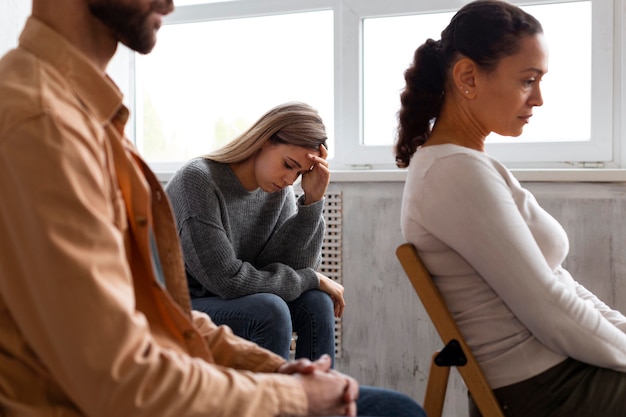 Mulher triste sentada em uma cadeira em uma sessão de terapia de grupo