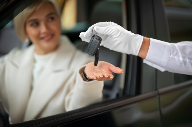Mulher trocando chaves de carro com manobrista de estacionamento