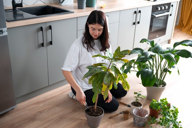 Mulher trocando os vasos de suas plantas em casa durante a quarentena