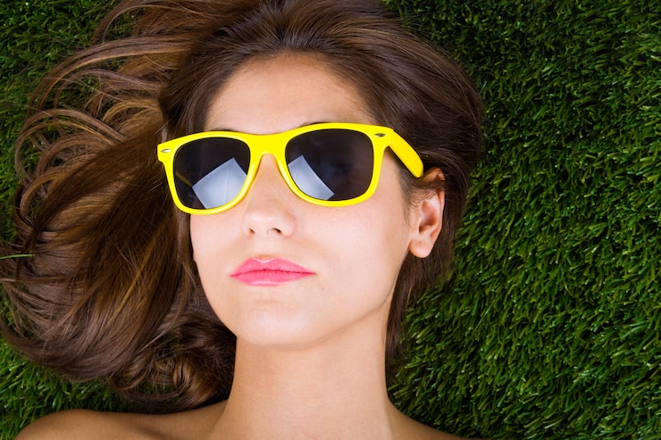 Foto grátis mulher tumbada sobre a hierba com gafas de sol