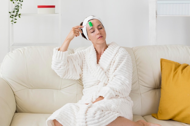 Mulher usando a bandana e massageando o rosto em plano geral