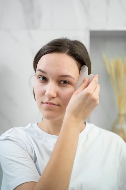 Mulher usando a ferramenta gua sha plano médio