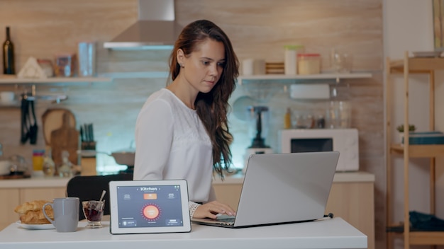 Mulher usando aplicativo de iluminação sem fio inteligente ativado por voz no tablet