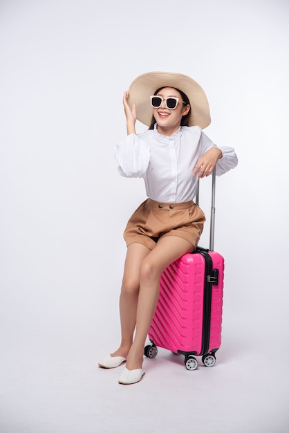 Mulher usando chapéu, óculos e alças de malas para viajar