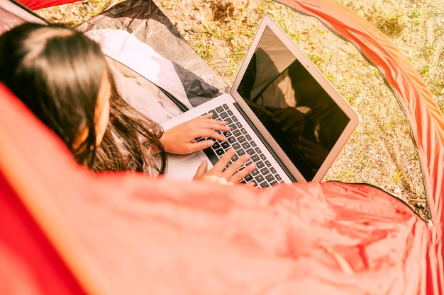 Mulher, usando computador portátil, enquanto, descansar, em, acampamento