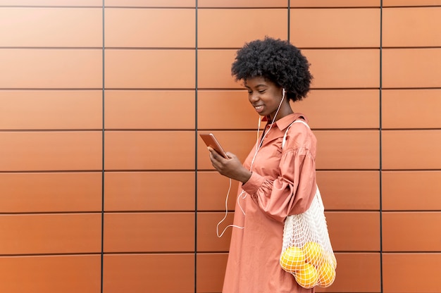 Foto grátis mulher usando fones de ouvido enquanto segura o smartphone