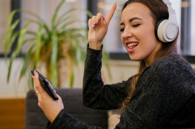 Mulher usando fones de ouvido, olhando para o telefone e cantando