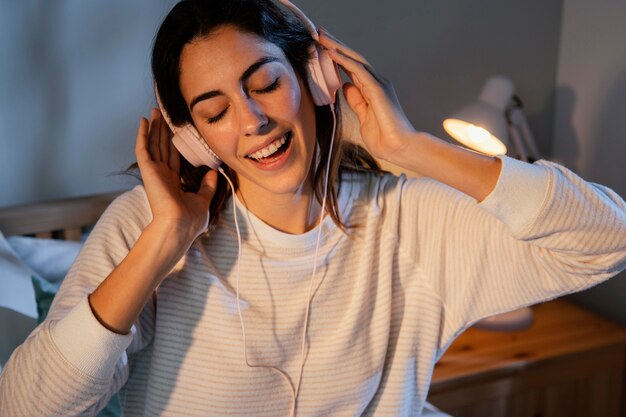 Mulher usando fones de ouvido para música em casa na cama