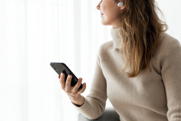 Foto grátis mulher usando fones de ouvido sem fio e um telefone celular