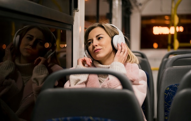 Mulher usando fones de ouvido, sentado no ônibus