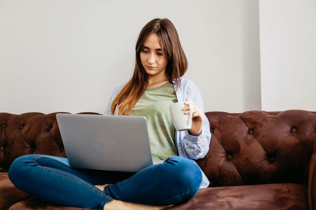 Mulher usando laptop e bebendo café