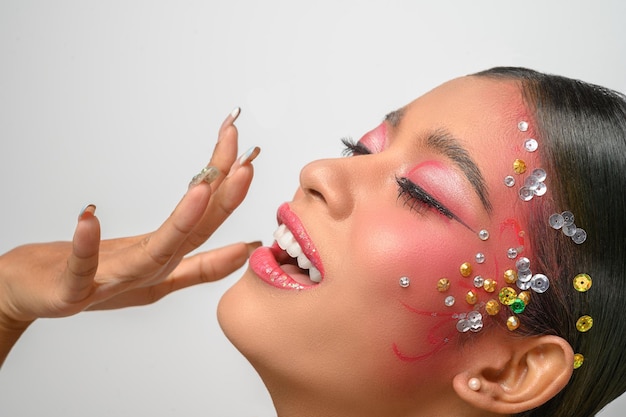 Foto grátis mulher usando maquiagem rosa e enfeites no rosto isolado no branco