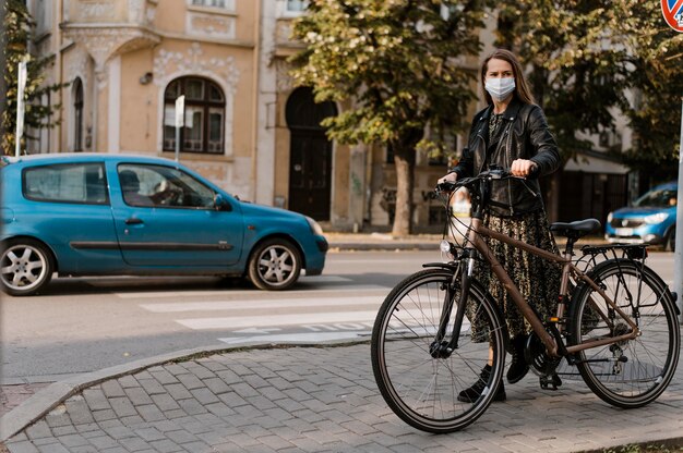 Mulher usando máscara médica e visão de longo prazo de bicicleta