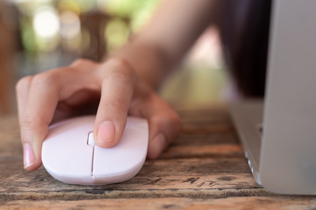 Mulher usando o mouse de computador com o laptop.