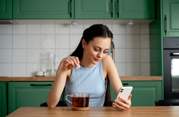 Mulher usando smartphone em uma cozinha verde
