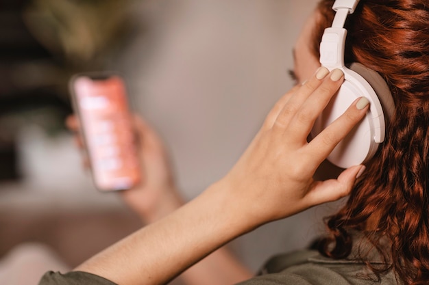 Foto grátis mulher usando smartphone moderno e fones de ouvido no sofá em casa