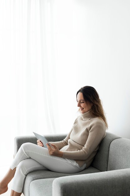 Mulher usando tablet digital em um sofá