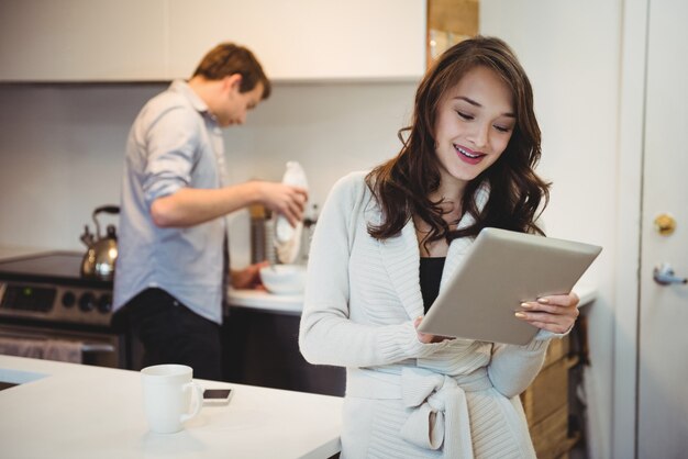 Mulher usando tablet digital enquanto homem trabalha atrás