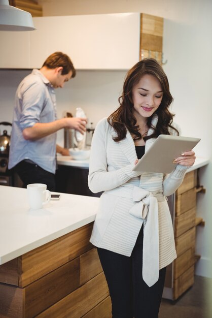 Mulher usando tablet digital enquanto homem trabalha em segundo plano