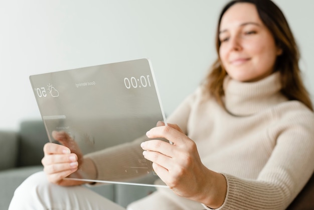 Mulher usando tablet transparente em uma poltrona tecnologia inovadora