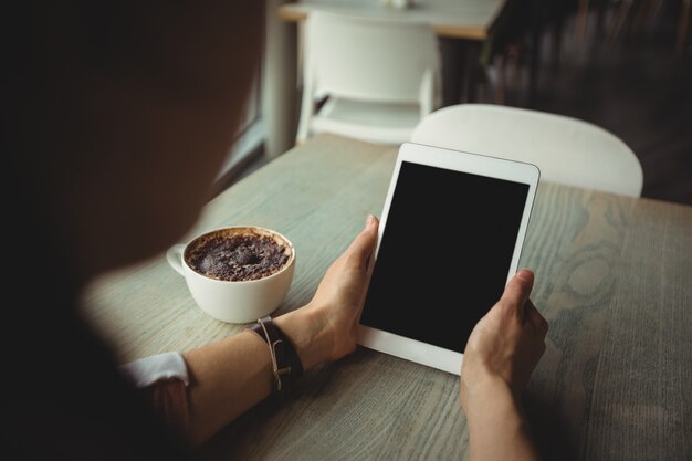 Mulher, usando, tablete digital, enquanto, tendo, xícara café