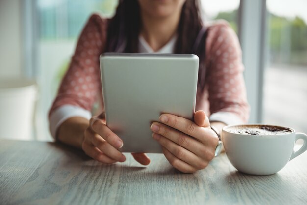 Mulher, usando, tablete digital, enquanto, tendo, xícara café