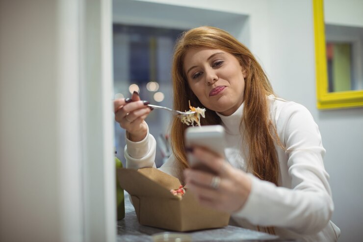 Foto grátis mulher usando telefone celular enquanto come salada