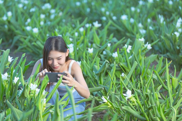 Mulher usando telefone celular para tirar foto no jardim de flores.