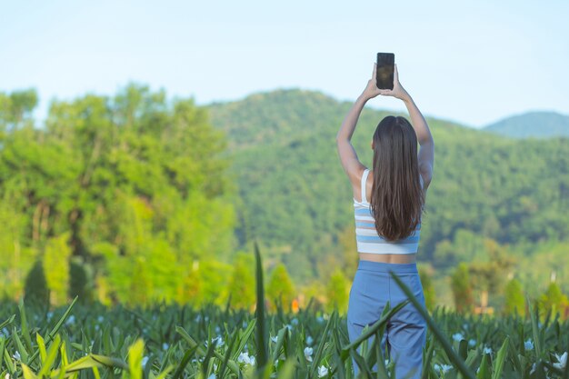 Mulher usando telefone celular para tirar foto no jardim de flores.