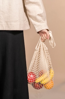 Mulher usando uma sacola de rede para carregar frutas