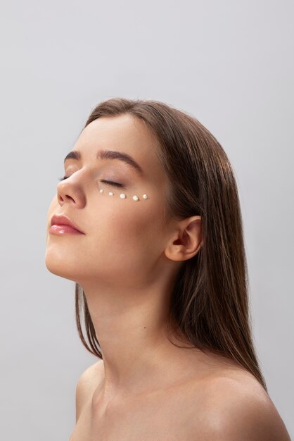 Mulher usando vista lateral de creme para os olhos
