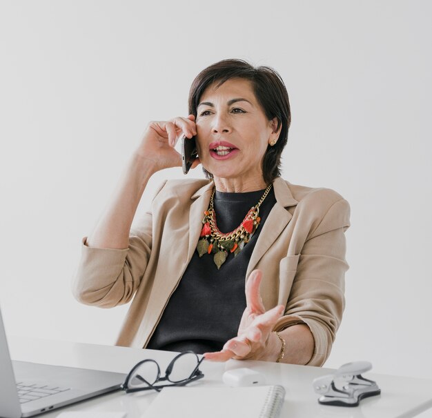 Mulher velha com colar falando ao telefone