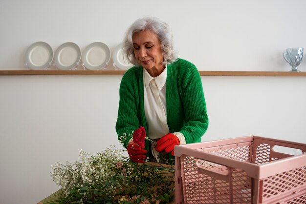 Mulher velha de médio porte a cuidar de plantas.