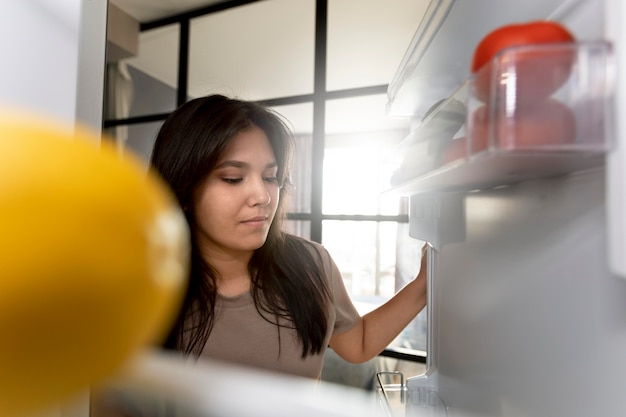 Foto grátis mulher verificando o interior da geladeira em casa