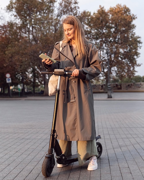 Mulher verificando o smartphone enquanto está em uma scooter elétrica ao ar livre