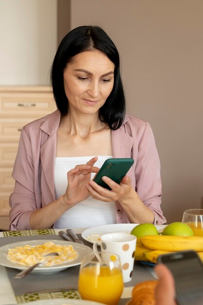 Mulher verificando o telefone enquanto espera pelo café da manhã