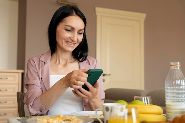 Mulher verificando o telefone enquanto espera pelo café da manhã