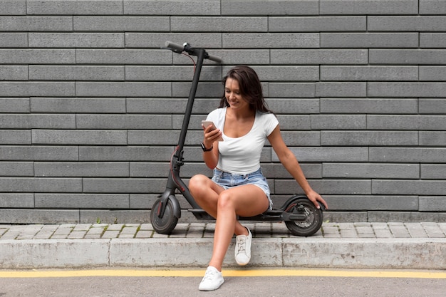 Mulher verificando o telefone enquanto está sentada na scooter