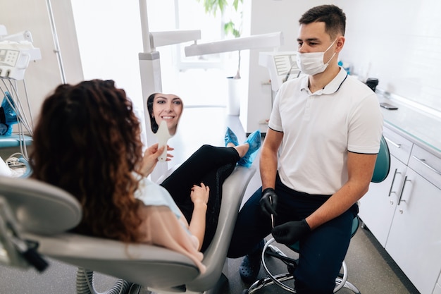 Mulher, verificando seu sorriso no espelho no dentista