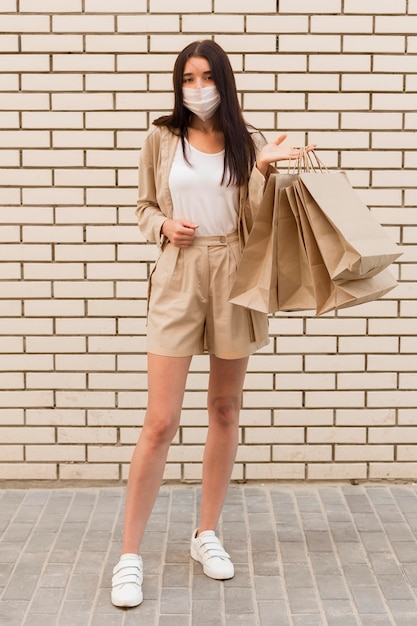 Foto grátis mulher vestida de forma elegante segurando sacolas de compras e usando máscara