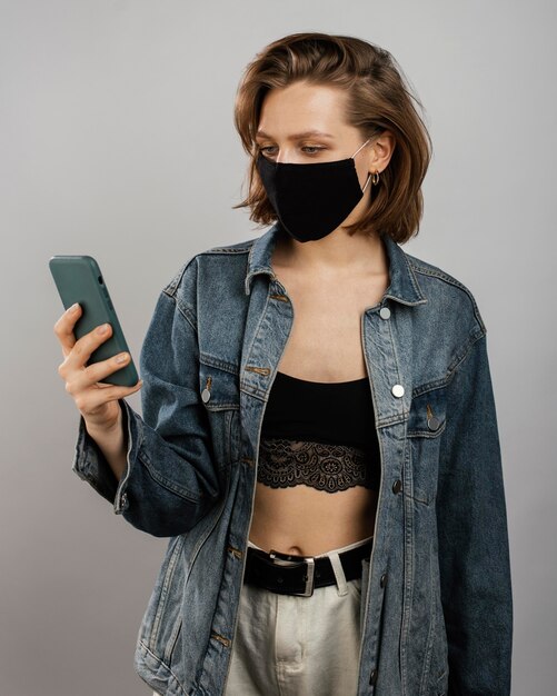 Foto grátis mulher vestindo jaqueta jeans e máscara enquanto usa o celular