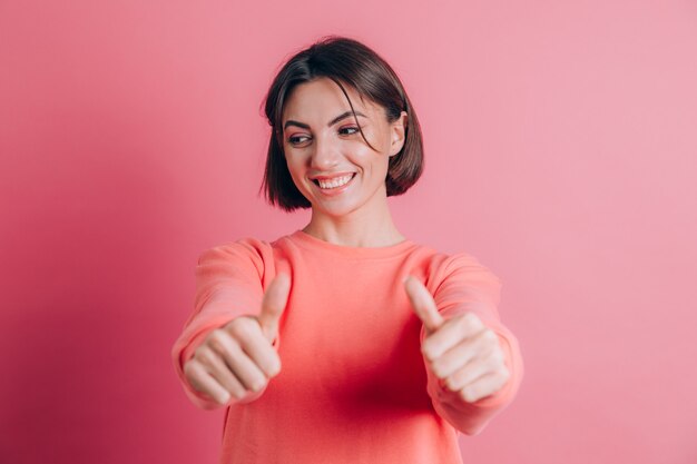 Mulher vestindo uma blusa casual no fundo, aprovando um gesto positivo com a mão, polegar para cima, sorrindo e feliz pelo sucesso