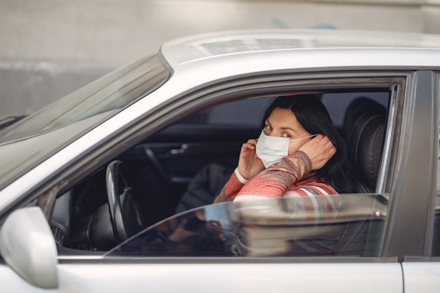 Mulher vestindo uma máscara protetora, sentado em um carro