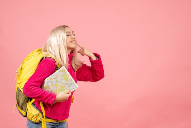 Foto grátis mulher viajante com vista frontal com mochila mostrando o sorriso