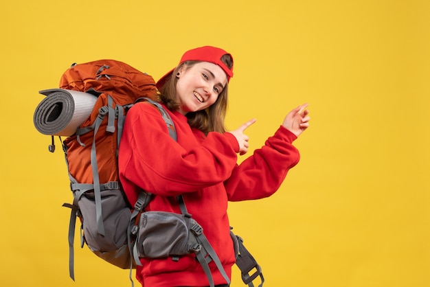 Mulher viajante feliz com mochila apontando os dedos para trás