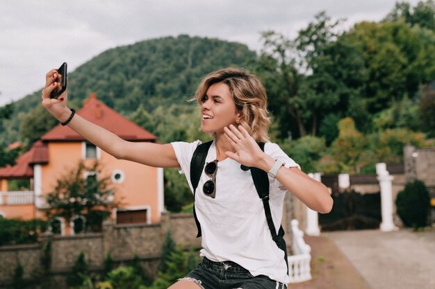 Mulher viajante muito charmosa fazendo selfie em smartphone sobre a montanha em um dia bom de sol. conceito de viagens, férias, viagem