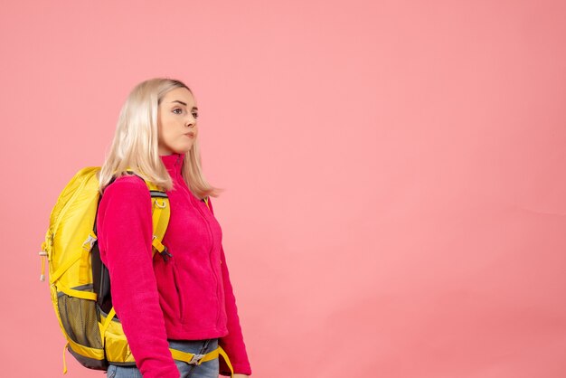 Mulher viajante nervosa com mochila em pé na parede rosa