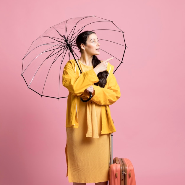 Mulher viajante olhando para longe enquanto segura um guarda-chuva