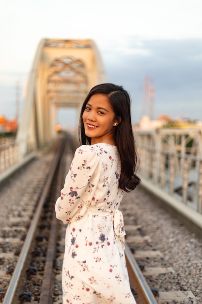 Mulher vietnamita sorridente com cabelo preto em pé sobre uma ponte velha